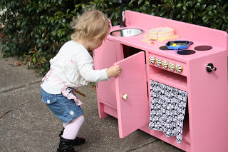 Play Kitchen from the thrift store painted pink and little girl playing with it