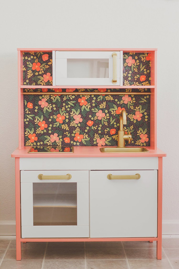 IKEA Play Kitchen with floral wall paper on the back wall