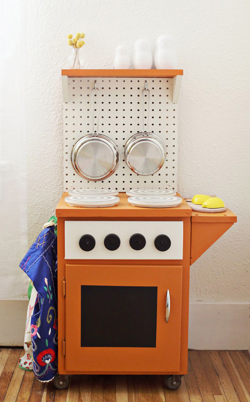 Rolling cabinet made to look like a stove and oven with pegboard wall to hang toy pots and pans