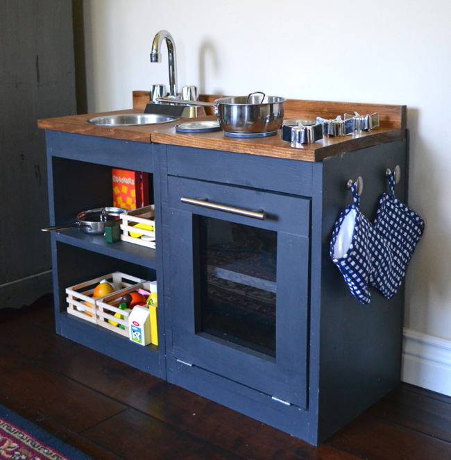 Dark blue play kitchen with wood top, sink and play stove and oven