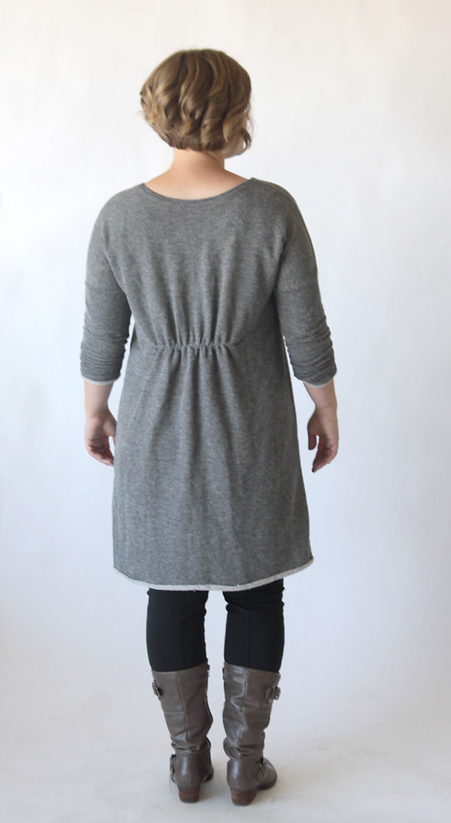 A woman wearing a sweater dress with gathered waist in the back