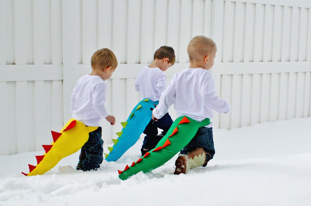 Little boys in the snow wearing fabric dinosaur tails