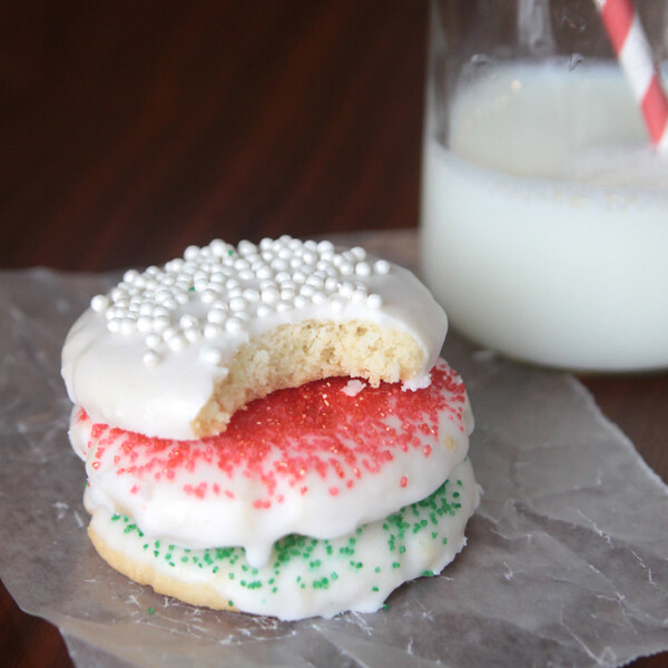 A stack of glazed sugar cookies, top one with a bite taken out of it