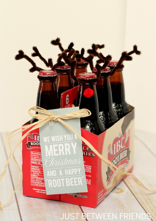 Bottles of root beer decorated with pipe cleaners and red pom pom to look like reindeer with gift tag