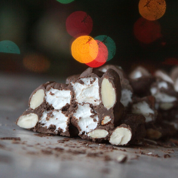 A close up of a piece of rocky road candy in front of Christmas lights