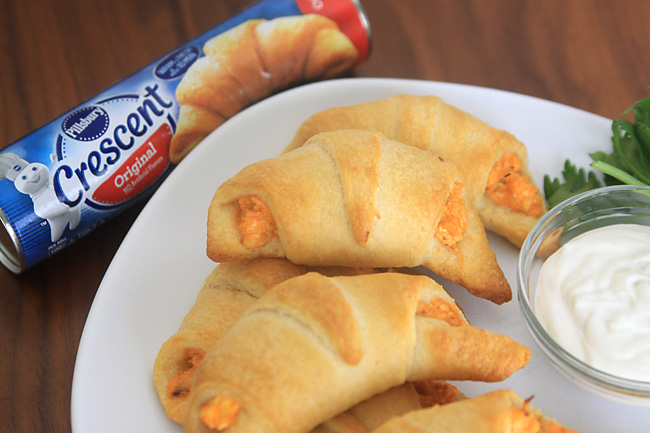 Buffalo chicken rollups on a plate, tube of crescent roll dough