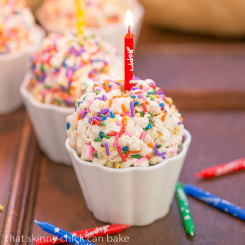 Popcorn ball decorated with sprinkles and topped with a candle