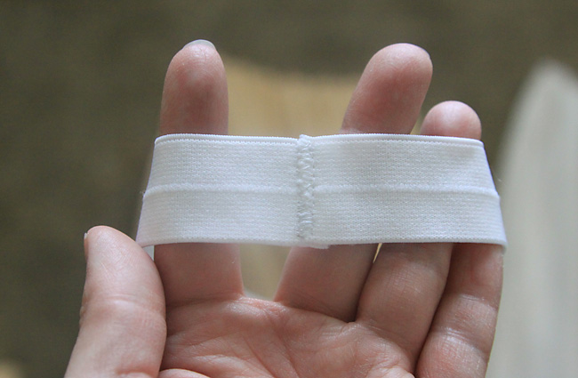 Hand holding a strip of elastic that\'s been sewn together