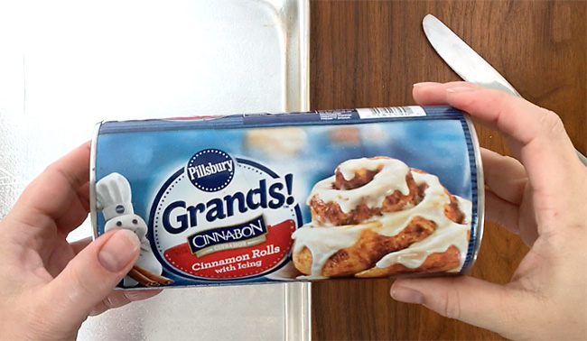 Hands holding a tube of Grands! cinnamon rolls