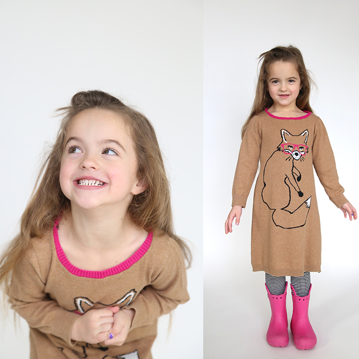 A girl wearing a sweater dress with a fox on it and pink boots
