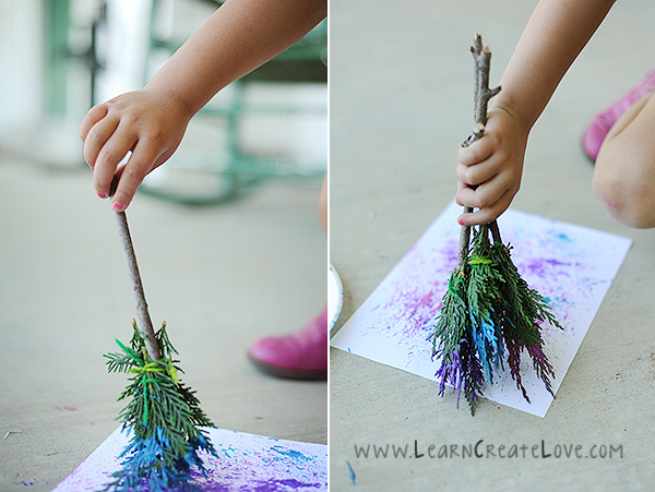 Child\'s hand painting with paintbrush made from branches