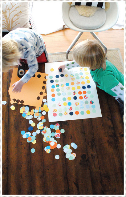 Boys placing circles of pattern paper on white background for an art project