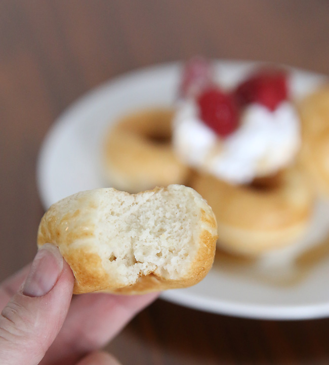 Hand holding a pancake donut with a bite taken out