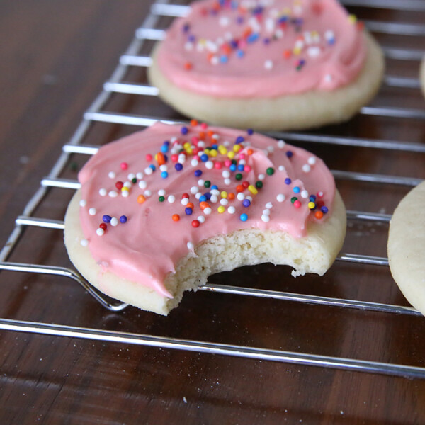 Soft sugar cookies with pink cream cheese frosting on a cooling rack