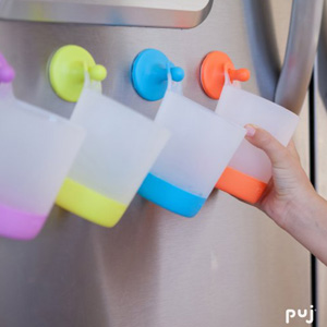 Plastic cups that hang from hooks adhered to the fridge