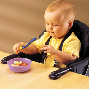 A baby sitting in a high chair that attaches to the edge of the table