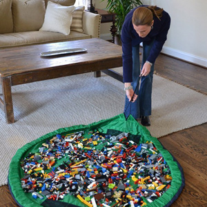 A person pulling on a circular mat full of legos that will cinch into a sack