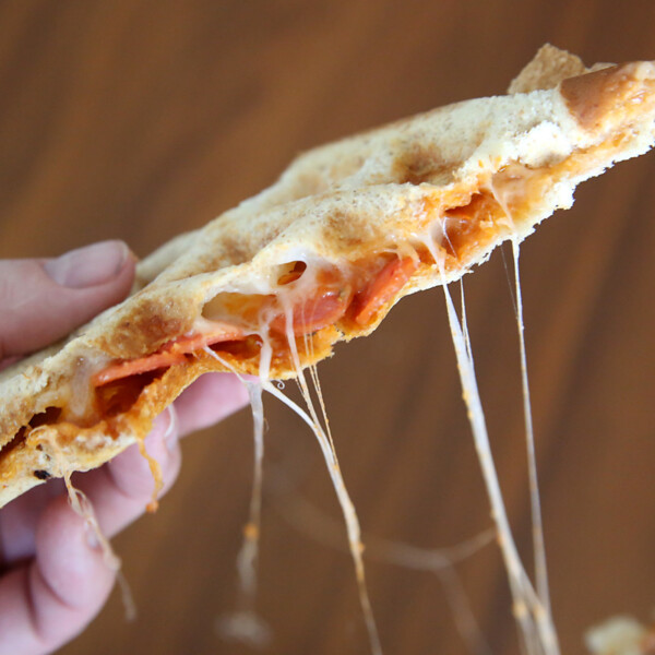 Hand holding half of a pizza sandwich made on a waffle iron