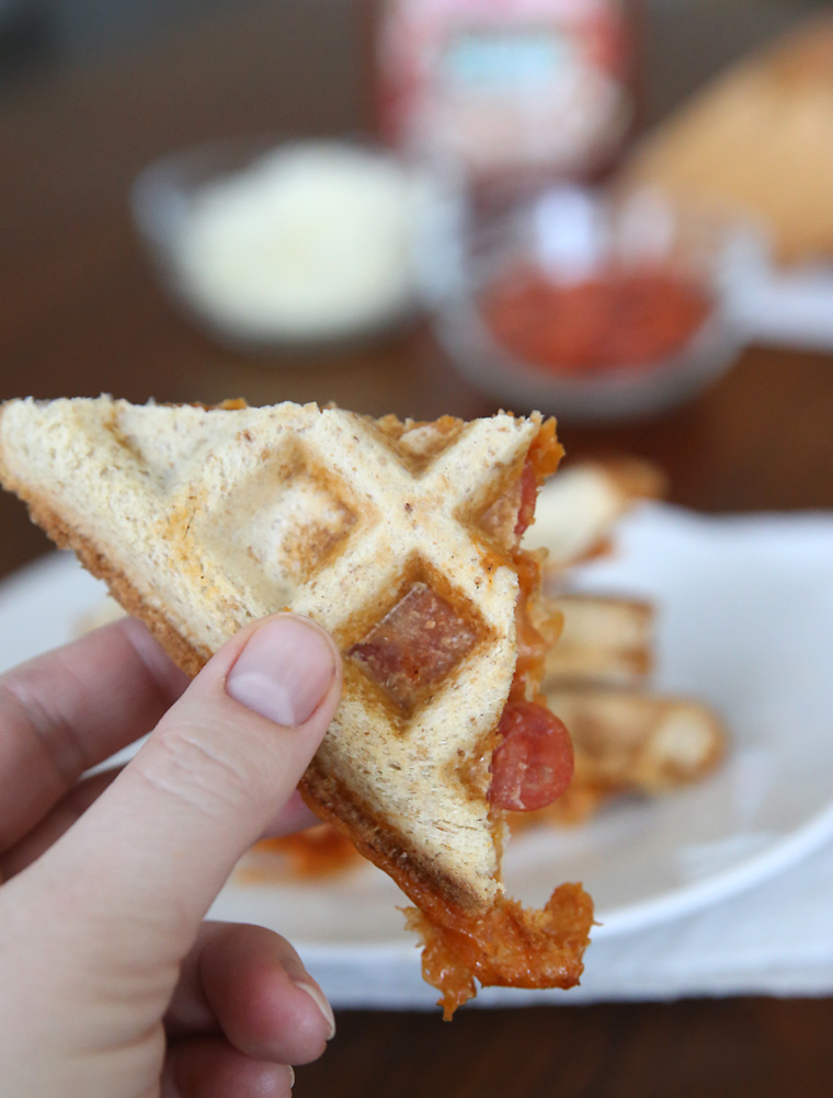 Hand holding a pizza wafflewich quarter