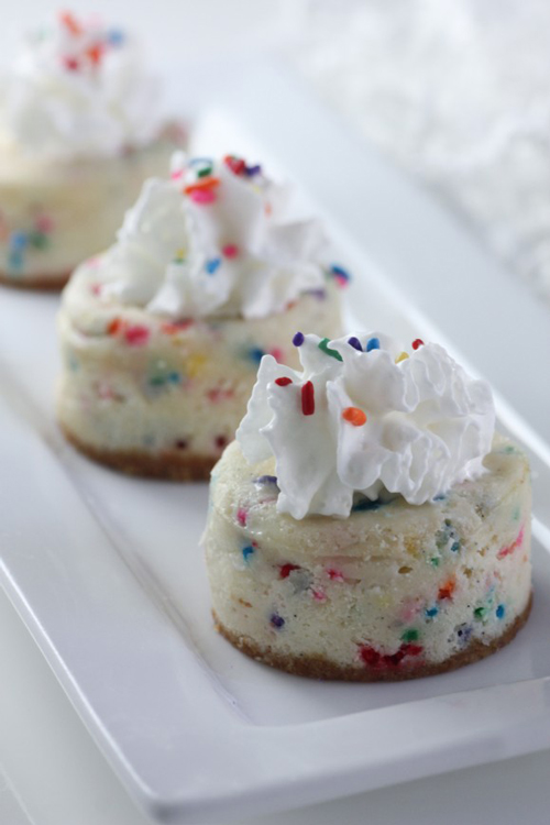 mini cake batter cheesecakes with whipped cream and sprinkles