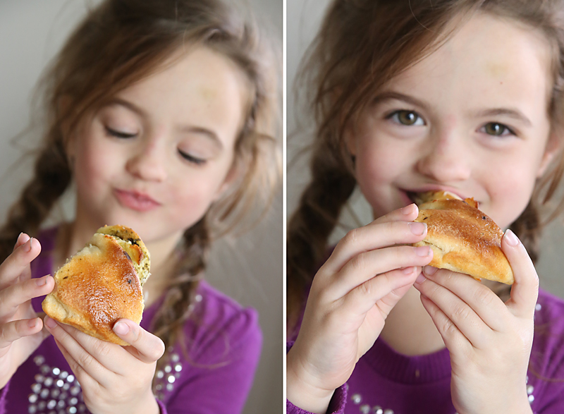 A young girl eating a piece of pesto chicken tear and share