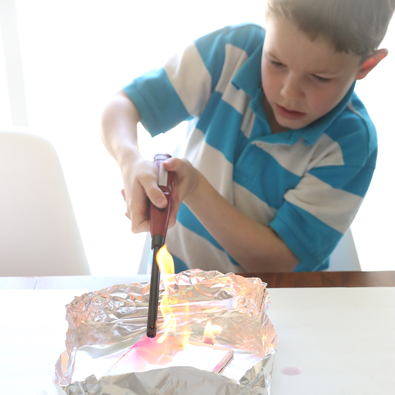 Boy using a lighter to set fired to the alcohol on the tile