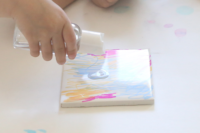 Hand pouring alcohol on colored tile