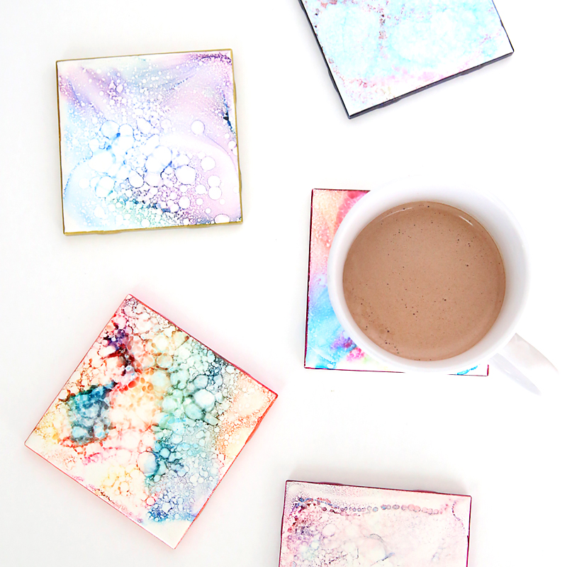 DIY coasters made from white tiles decorated with marbled inks; cup of cocoa on a coaster