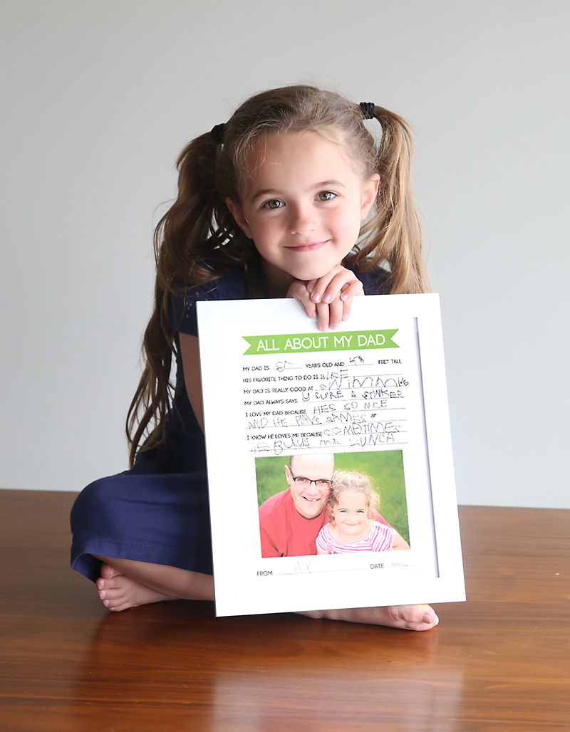 little girl holding a framed All About my Dad questionnaire