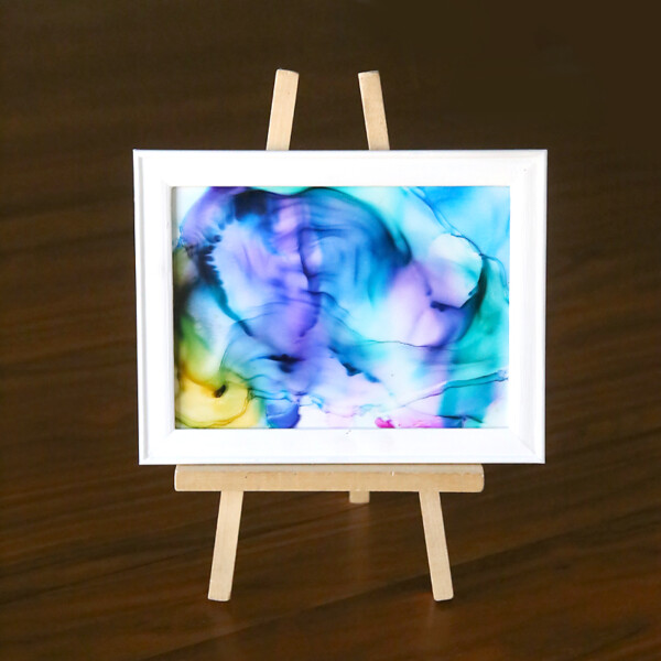 A piece of glass with marbled ink design on it in a frame