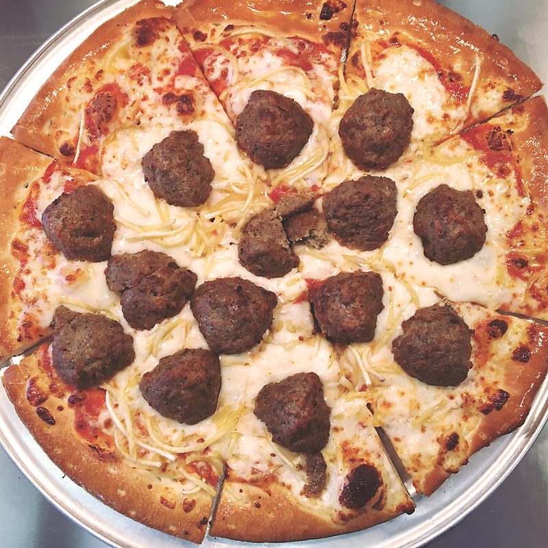A close up of a meatball pizza