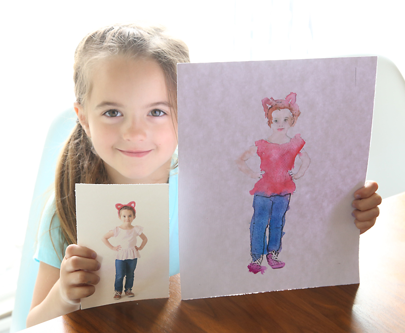 Girl holding a coloring page that\'s been made from a picture of her