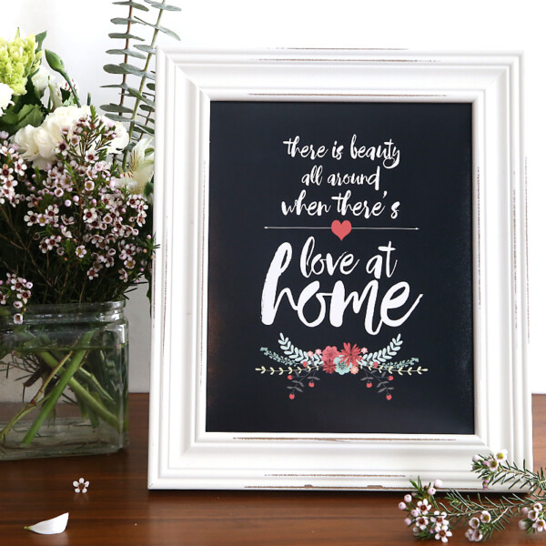 A framed chalkboard sign with the quote "there is beauty all around when there's love at home"