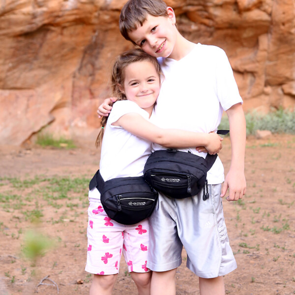 A girl and boy wearing fanny packs hugging each other