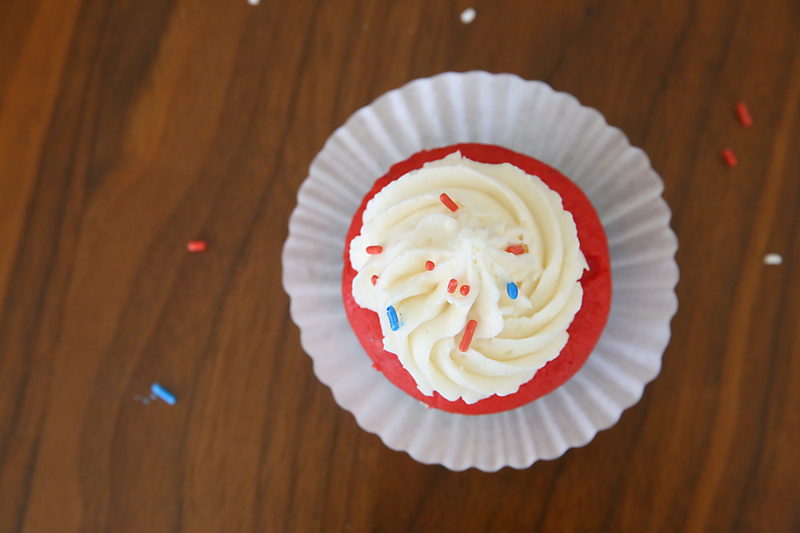 Red cupcake with white frosting and sprinkles