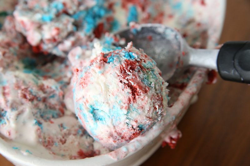 Red white and blue cake ice cream in a bowl with a scoop