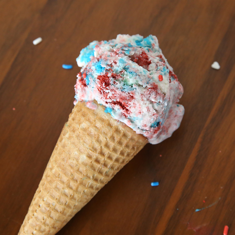 Ice cream cone with red and blue cake chunks mixed into it