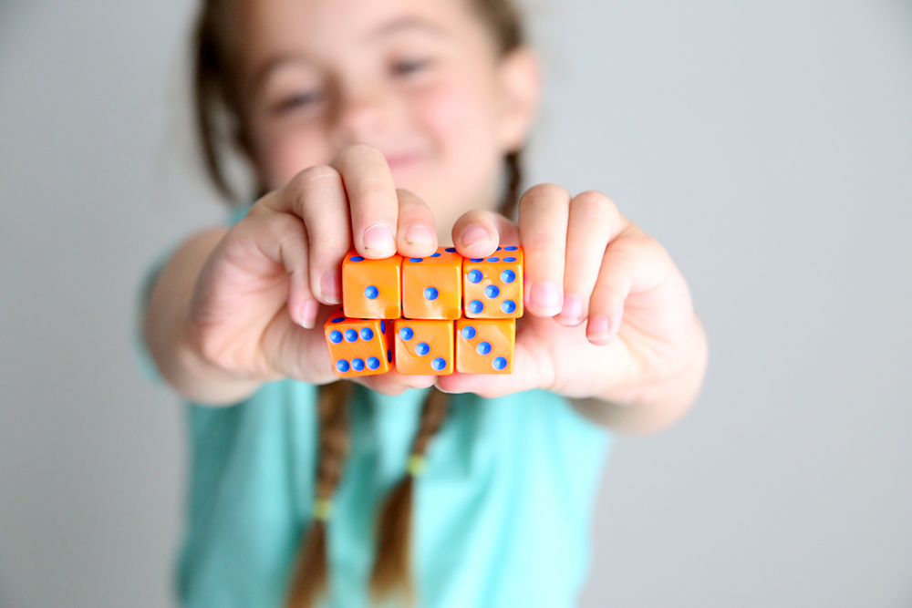 A little girl holding six dice