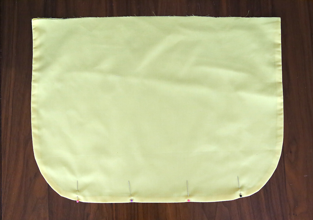 Curved bottom edge of apron hemmed, pinned in 4 places