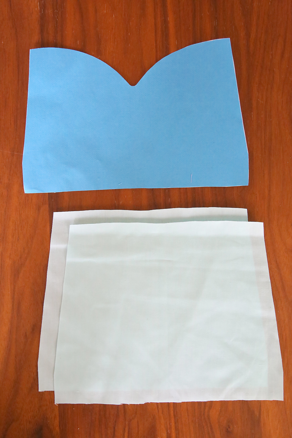 Apron bodices cut from light blue fabric, over bodice cut from darker blue fabric
