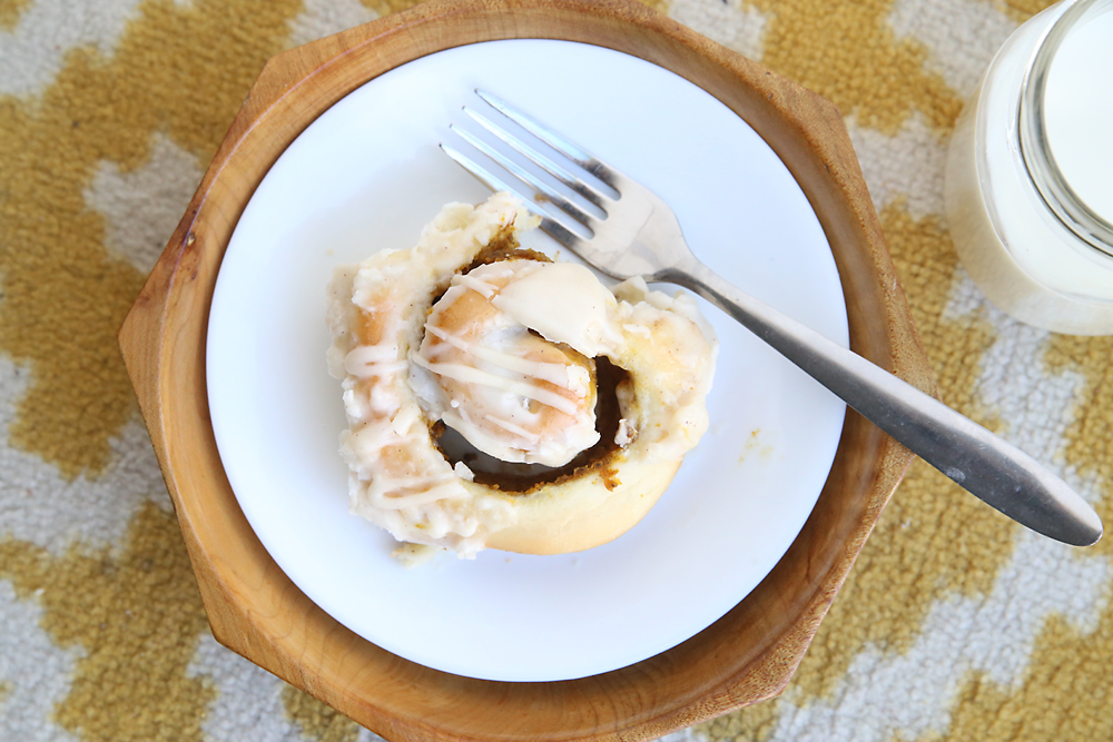 A pumpkin pie cinnamon roll on a plate with a fork