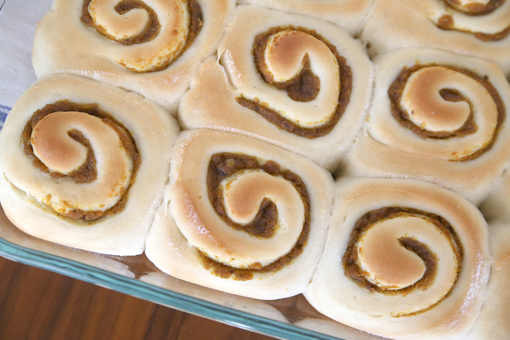 Golden brown pumpkin pie cinnamon rolls in a baking dish