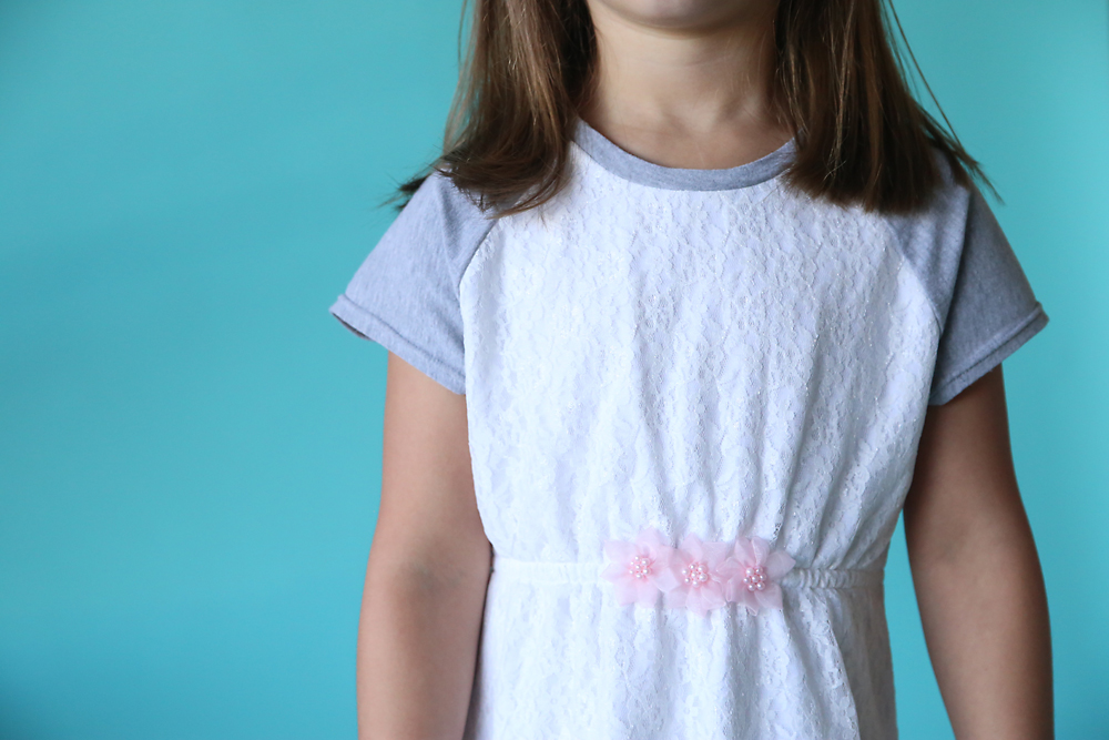 Closeup of the waistline on the dress with three pink flowers attached