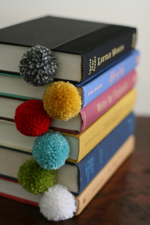 Stack of books with homemade pom pom bookmarks in them