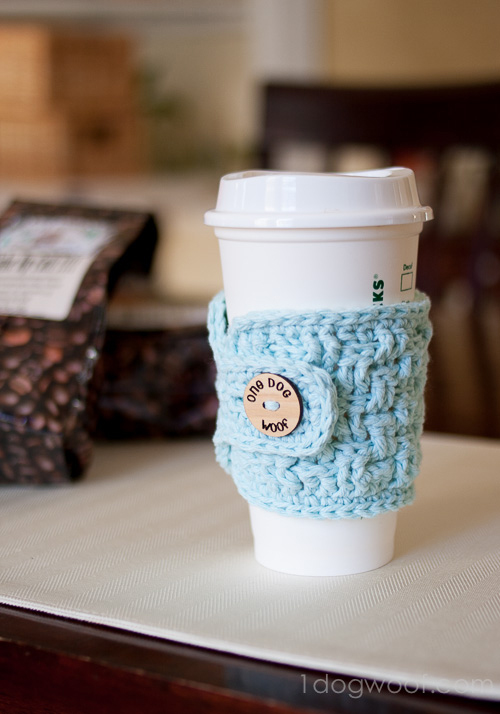 A cup of coffee on a table with a crocheted cozy around it