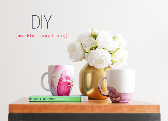 Mug dipped in paint, next to a vase of flowers on a table