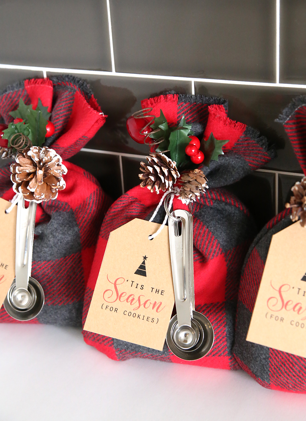 Cookie mix gift sacks with tags and measuring spoons lined up against a wall