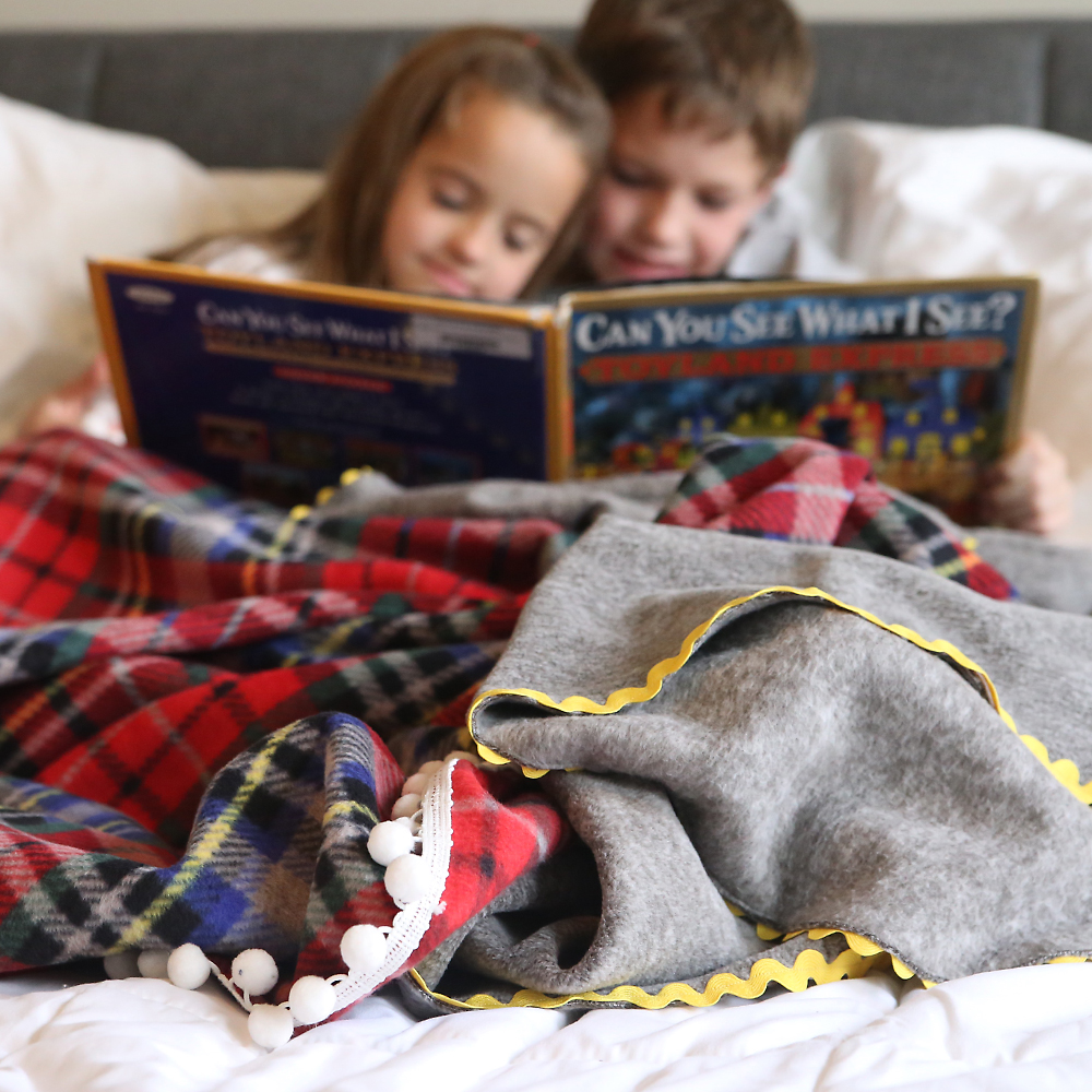 Little kids reading a book with homemade fleece blankets