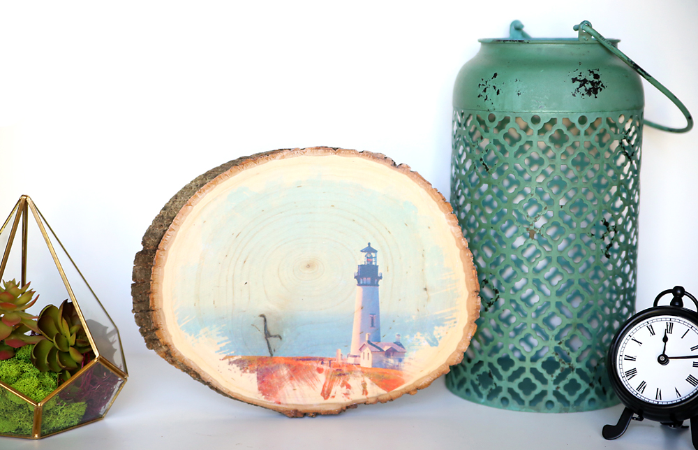 A wood slice with a photo of a lighthouse transferred onto it