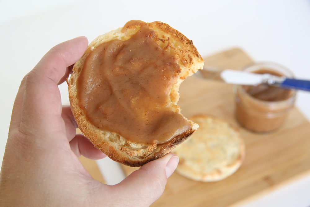 Hand holding an English muffin spread with caramel apple butter